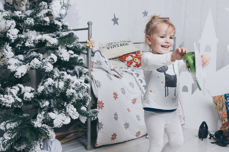 漂亮的小女孩开心她坏附近圣诞树在房间里。演奏萨克斯管和跳舞
