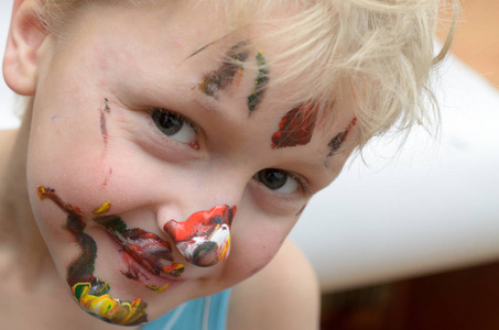 孩子的脸上沾上了油漆, 笑得滑稽而欢快。