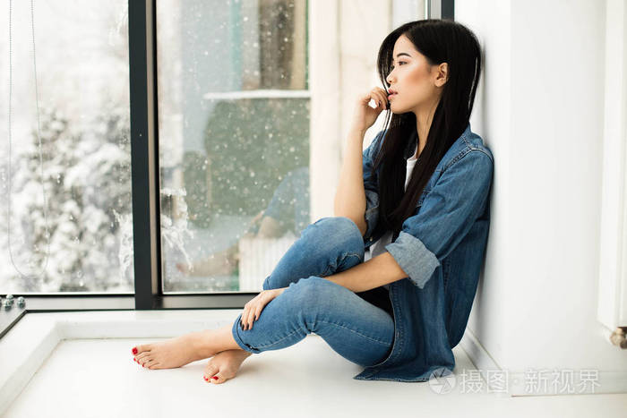 亚洲女孩坐在地板上的窗边