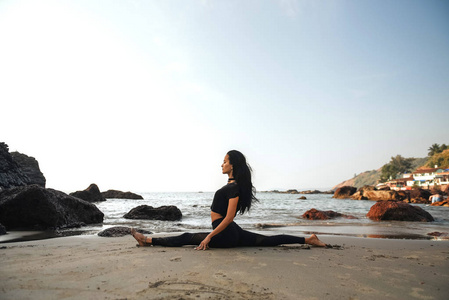 ung frisk kvinna utvar yoga p stranden vid solnedgngen