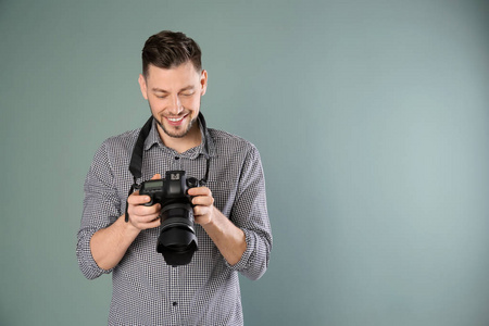 男摄影师用相机在灰色的背景上