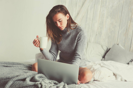 年轻的博客写手或商业女性在家里和社交媒体一起工作, 清晨在床上喝咖啡。现代生活在斯堪的纳维亚内部, 休闲生活方式