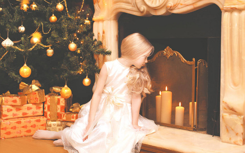儿童礼品盒圣诞树和 firep 附近的小女孩