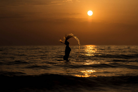 女性在夕阳中回鞭打她的头发