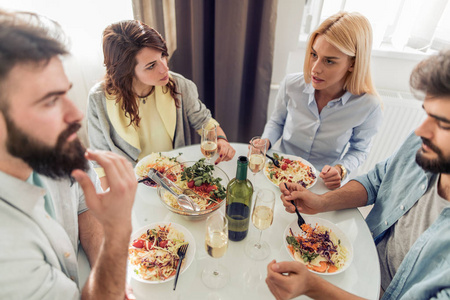 朋友们在家里吃午饭。一群快乐的人戴着眼镜, 在家里聊天和吃健康的饭菜。