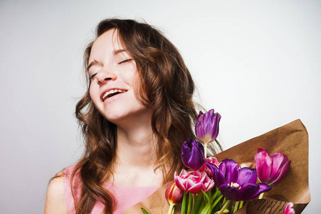 快乐微笑的女孩捧着一大束芬芳的花朵, 庆祝世界妇女节