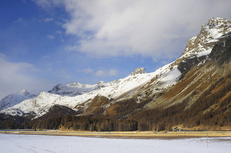 恩加丁谷在瑞士锡尔斯玛丽亚村庄与阿尔卑斯山和结冰的湖面上的雪