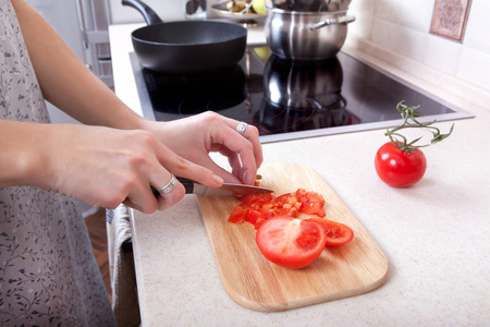女人削减西红柿用小刀在厨房的桌子上