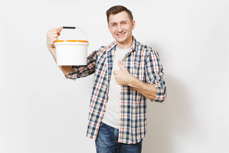 年轻的微笑英俊的男子拿着空的油漆桶与复制空间和显示拇指上孤立的白色背景。设备, 装修房配件。修复主页概念