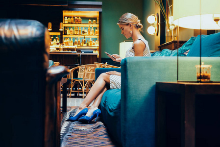 年轻漂亮的金发女郎在咖啡店休息时使用手机