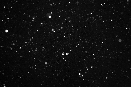 在黑色背景上漫天飞舞的雪花照片