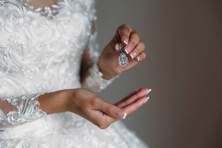 Earrind 在黑色背景上新娘的手中。珠宝首饰的概念