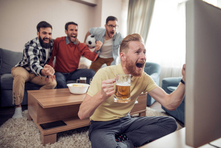 一群朋友在电视上观看足球比赛并庆祝进球