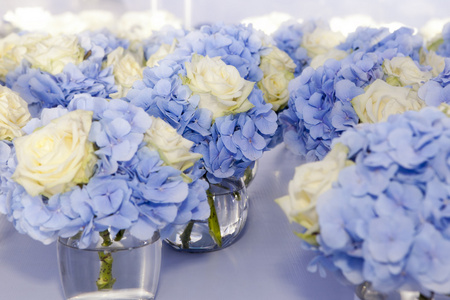 美观 精致的玻璃花瓶中的白色玫瑰和蓝色绣球花的花束