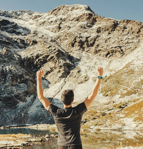 男人抬起手去观赏风景的早上山。instagram 过滤器，方形的照片