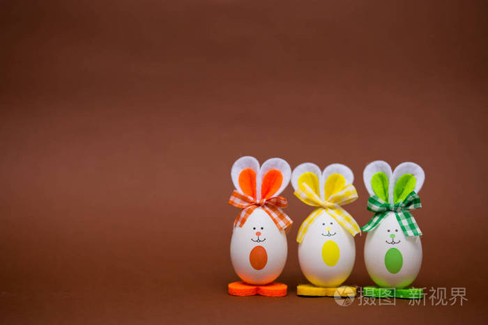 多彩多姿的滑稽的蛋以可爱的兔子的形式在褐色背景.复活节快乐.