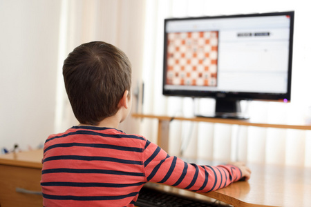小男孩玩电脑象棋照片