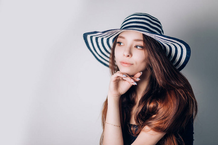 美丽的时尚女人在一顶帽子看着侧面白色背景
