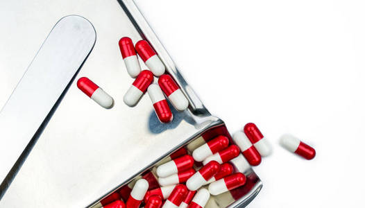 红色, 白色抗生素胶囊药片与阴影在不锈钢药物托盘。耐药性抗菌药物使用合理卫生政策和健康保险理念