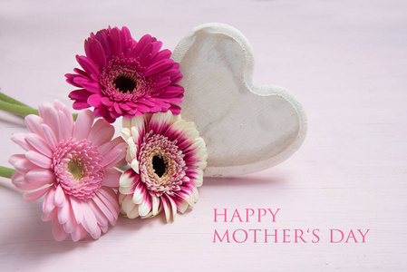 粉红色的花朵和白色的彩绘木心在一个粉彩色的背景, 爱情符号与文本快乐母亲节, 复制空间