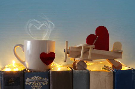情人节背景。木制玩具飞机心脏和杯子在旧书