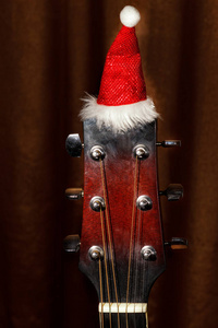 在灰色的背景下，圣诞歌曲的吉他上的红色圣诞帽子