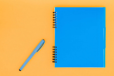 橙色背景上带有手柄的蓝色笔记本。平躺模板。文本位置