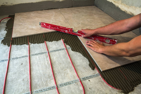 瓷砖和工具的工.工人手安装地板照片