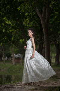 亚洲女孩穿着婚纱时在森林里