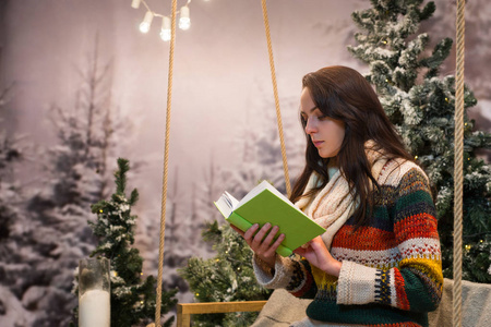 浪漫的年轻女子坐在秋千机智的同时阅读一本书