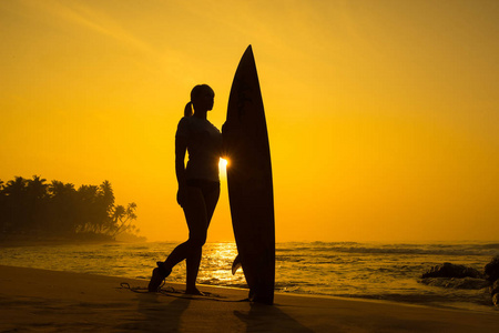 冲浪冲浪女孩看着海洋沙滩日落。剪影 w