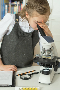 在使用显微镜的科学课的小女孩