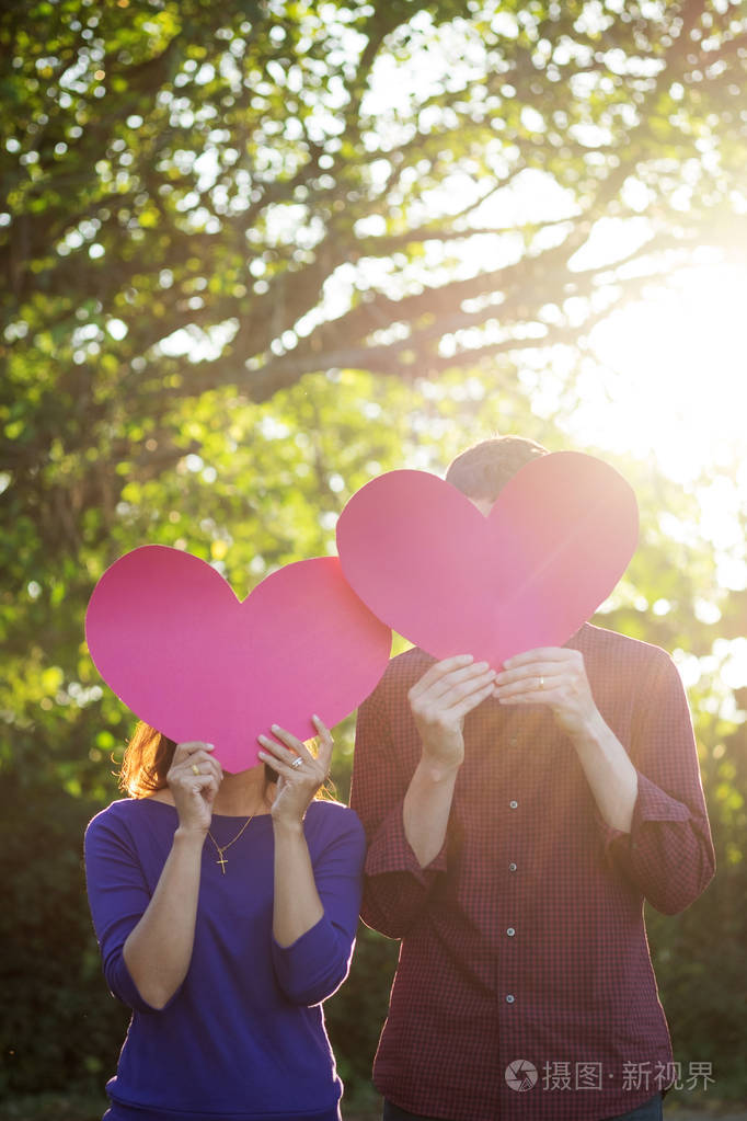 恩爱的夫妻.美丽年轻的爱夫妇拿着纸做的爱心