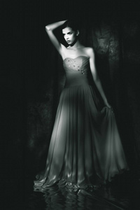 在黑暗背景下的晚礼服的美丽的妇女