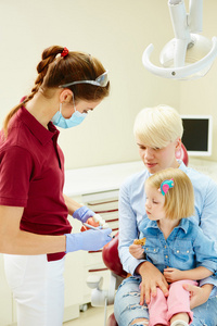 向年轻的病人和她的母亲解释模型的儿科牙医