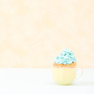 蛋糕与蓝色奶油装饰在板黄色柔和的正方形横幅。简约静物概念