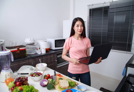 厨房里的女人做饭和看笔记本电脑