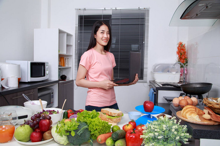 厨房里的女人做饭和看笔记本电脑