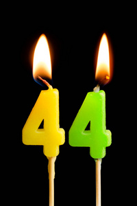 燃烧蜡烛的形式为44四十四 (数字, 日期) 的蛋糕孤立的黑色背景.