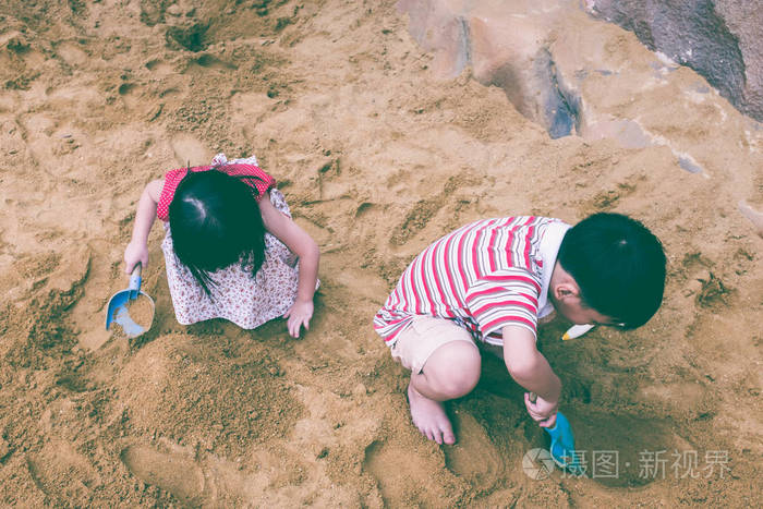 顶视图。快乐的弟弟和妹妹玩沙子。复古色调
