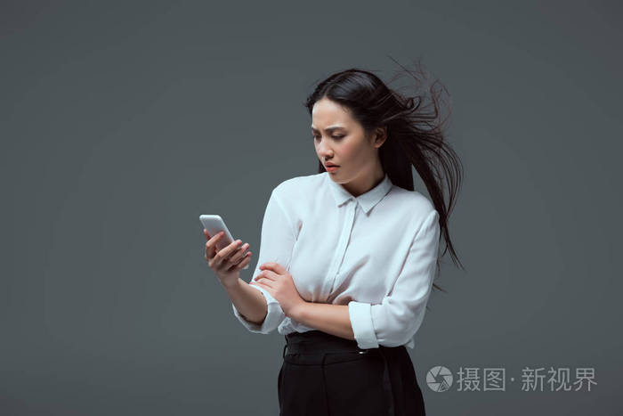 严重的年轻亚洲妇女使用智能手机隔离灰色