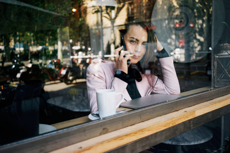 年轻的现代妇女谈论智能手机, 而在咖啡馆吃早餐
