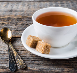 白色茶杯和茶托棕色甘蔗糖在一个质朴的木质背景下
