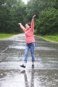 雨城快乐的女孩在水坑里跳