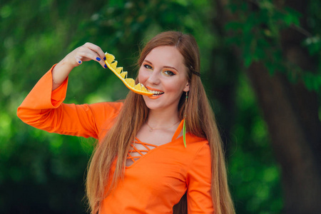 美丽的红色头发妇女的肖像举行多汁的美味橙在夏季绿色公园