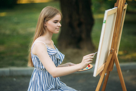 美丽的女孩画在公园的图片使用调色板与油漆和铲