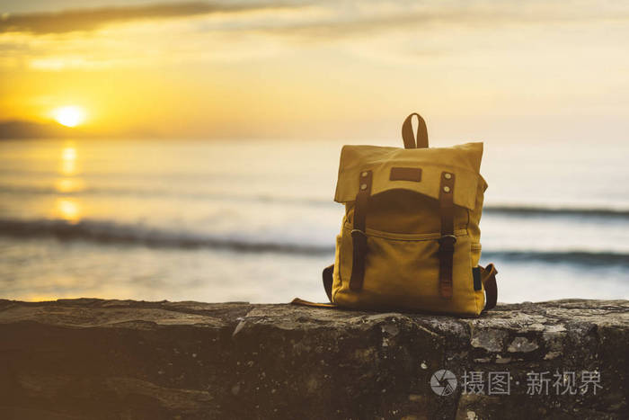 时髦的徒步旅行者黄色背包特写在背景蓝色海享受日落海洋地平线, 模糊
