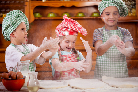 在厨房里的面粉三个有趣的年轻孩子握手