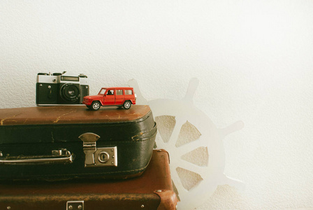 部分皮革旅行 valises 或旧手提箱与相机, 红色玩具汽车和老式白色方向盘。特写
