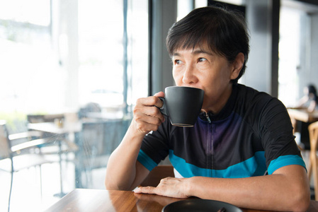 骑自行车球衣的资深亚洲妇女与咖啡